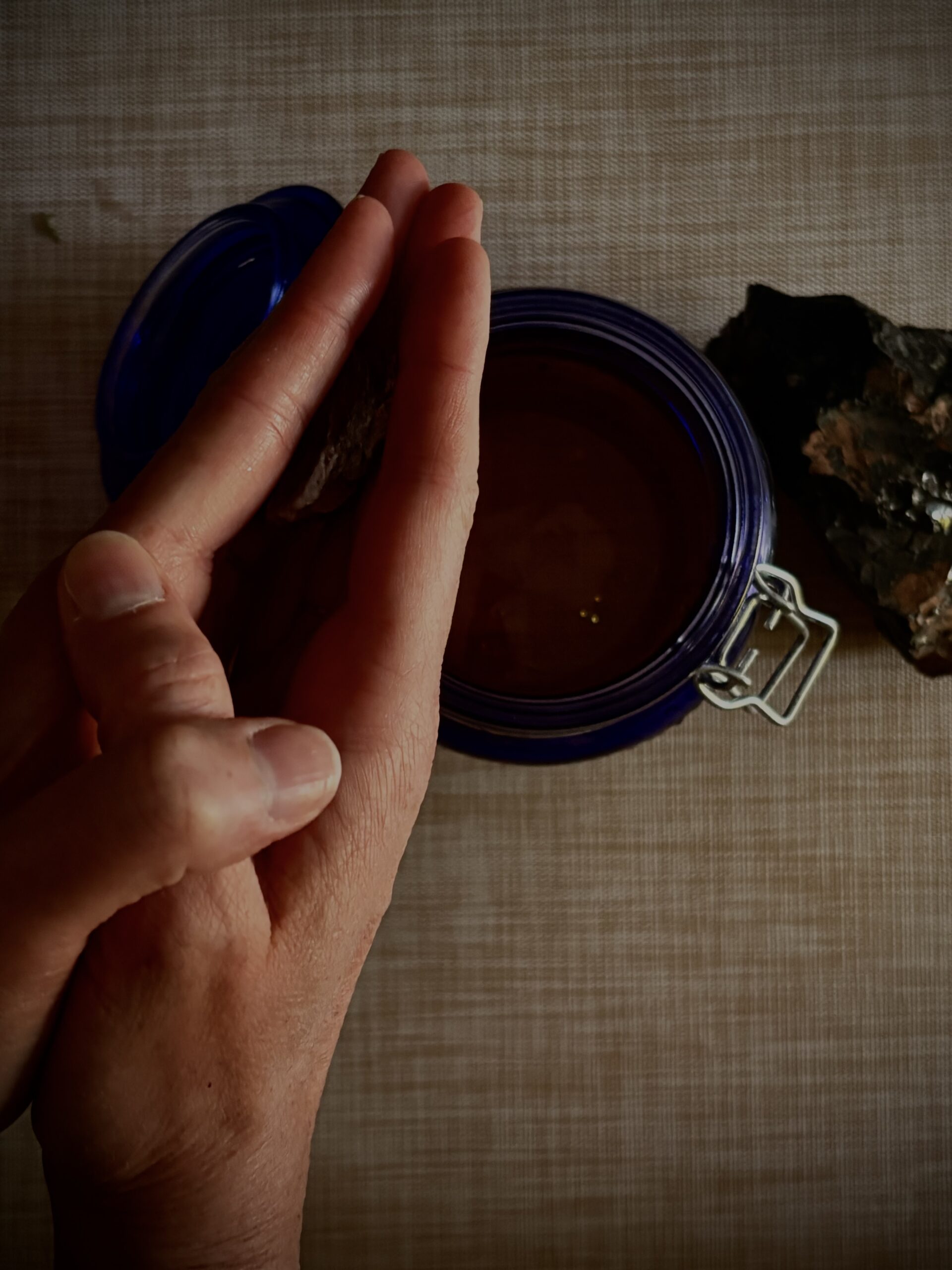 Hands working beside a blue glass vessel