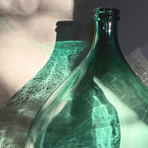 Green glass vessel illuminated by sunlight and shadow