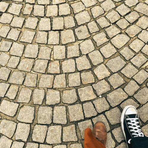 Cobblestone paths intersecting beneath two people walking
